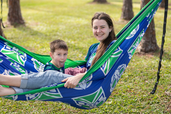 Warriors NRL recycled hammock with blue and green geometric print, shown in use outdoors with two children