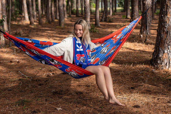 Recycled hammock with red and blue Knights NRL print, displayed in forest setting with integrated straps