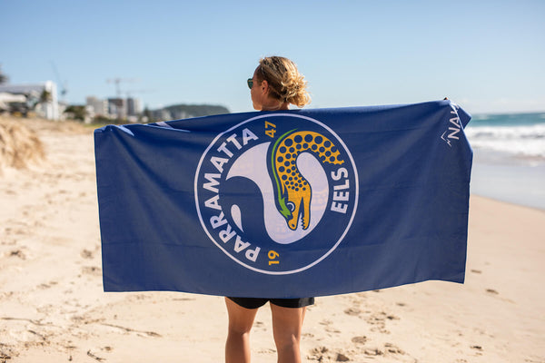 Blue Eels NRL recycled beach towel with logo design, held by person on sandy beach