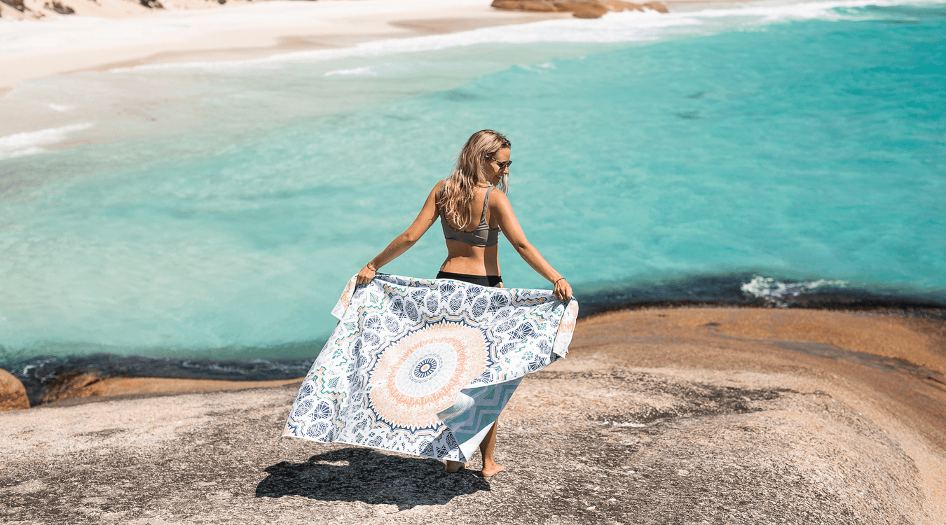Woman in sand free towel standing on a beautiful beach