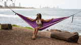 Woman relaxing in purple recycled hammock by the beach Nakie - Australia