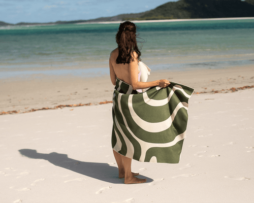 Woman drying herslef on Nakie sand-free recycled beach towel at Moreton Island, Australia