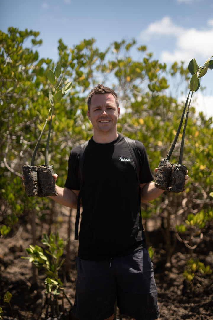 Nakie - Australia  Co-founder of Nakie holding four trees, symbolizing the company's commitment to planting four trees for every product sold, promoting sustainability and environmental conservation