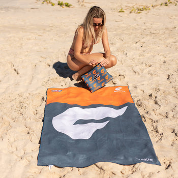 GWS Giants navy and orange beach towel with white logo, sand-free material, displayed on sand