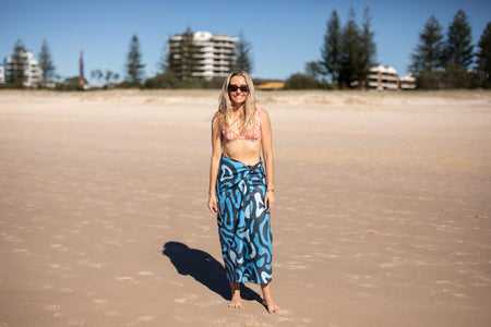 Blue abstract patterned recycled sand-free beach towel worn as wrap on beach model