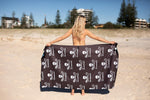 Black recycled beach towel with white skull and utensils print, held open on sandy beach preview #4