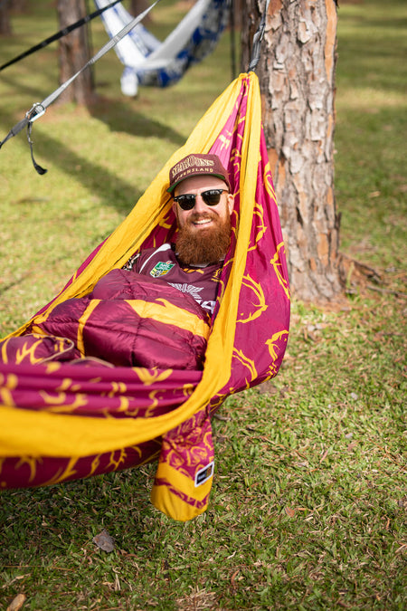 Man relaxing in a Nakie NRL Broncos Hammock outdoors