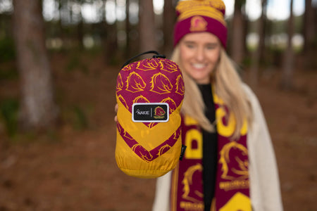Woman holding a Brisbane Broncos NRL Hammock packed away in its stuff sack for convenient storage