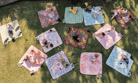 Aerial view captured by a drone showcasing Nakie's range of picnic blankets laid out in an array of colors and patterns, highlighting eco-friendly and durable designs